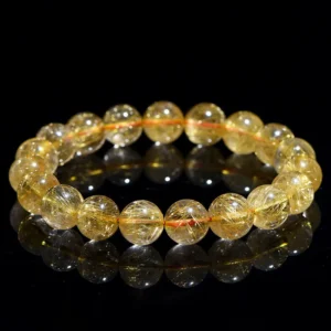 Natural Rutilated Quartz bracelet for Wealth & Success on black reflective background